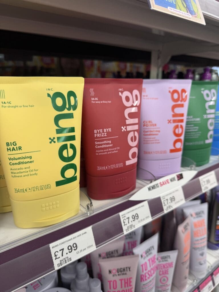 Colour-coded Being haircare packaging on a retail shelf, showing how packaging systems differentiate products within a range.
